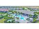 Aerial view of a resort-style pool with palm trees, seating, and a community clubhouse nearby at 6203 Grandview Hill Ct, Bradenton, FL 34203