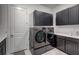 Contemporary laundry room featuring sleek, dark cabinetry, stacked washer and dryer units, and ample counter space at 6203 Grandview Hill Ct, Bradenton, FL 34203
