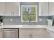 Close-up of the kitchen sink area with white cabinetry and blue decorative tile at 6343 Hollywood Blvd, Sarasota, FL 34231