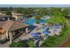 Aerial view of a resort-style pool featuring lounge chairs, blue umbrellas, and tropical plants at 6509 Grand Estuary Trl # 203, Bradenton, FL 34212