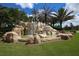 Beautiful waterfall feature at the entrance to the River Strand community, surrounded by palm trees and lush landscaping at 6509 Grand Estuary Trl # 203, Bradenton, FL 34212