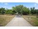 Long driveway leading to a charming home surrounded by lush trees and a well-maintained lawn at 6605 253Rd St E, Myakka City, FL 34251