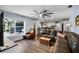 Spacious living room with wood-look tile flooring, leather seating, and access to kitchen and outdoor spaces at 6605 253Rd St E, Myakka City, FL 34251
