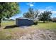 Exterior view of a well-maintained blue storage shed in a backyard setting with mature trees at 6605 253Rd St E, Myakka City, FL 34251