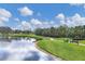 Scenic golf course featuring a tranquil pond, a winding cart path, and lush greenery under a partly cloudy sky at 6702 Drewrys Blf, Bradenton, FL 34203