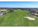 A wide, green golf course with scattered trees, a distant pond, and a clear blue sky, perfect for a relaxing game at 6702 Drewrys Blf, Bradenton, FL 34203