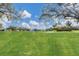 Scenic view of a green golf course with a pond, framed by trees against a backdrop of a partly cloudy sky at 6702 Drewrys Blf, Bradenton, FL 34203