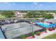 Aerial view of tennis courts, a pool, and a parking lot surrounded by trees and other buildings at 6702 Drewrys Blf, Bradenton, FL 34203