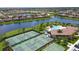 An aerial view shows a community with tennis courts, a pool and a clubhouse nestled near a lake at 7120 Quiet Creek Dr, Bradenton, FL 34212