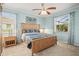Serene bedroom with blue walls, a wooden bed frame, ceiling fan, and abundant natural light for a relaxing retreat at 7120 Quiet Creek Dr, Bradenton, FL 34212