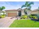 Charming single-story home with a tile roof, brick driveway, and lush tropical landscaping at 7120 Quiet Creek Dr, Bradenton, FL 34212