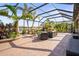 Relaxing screened-in patio with wicker furniture and a beautiful lake view framed by tropical palm trees at 7120 Quiet Creek Dr, Bradenton, FL 34212