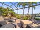 Screened patio with brick floors, wicker furniture, and a view of the lake and palm trees at 7120 Quiet Creek Dr, Bradenton, FL 34212