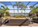A screened patio with brick floors and wicker furniture overlooks a tranquil lake view at 7120 Quiet Creek Dr, Bradenton, FL 34212