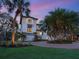 Beautiful two-story home with lush tropical landscaping, including mature palm trees, at dusk at 7333 Point Of Rocks Rd, Sarasota, FL 34242