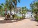 Elegant home exterior with a circular brick driveway, palm trees, and well-maintained landscaping at 7333 Point Of Rocks Rd, Sarasota, FL 34242