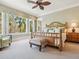 Spacious main bedroom with a bamboo-framed bed, many windows and views to the palms outside at 7333 Point Of Rocks Rd, Sarasota, FL 34242