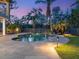 A backyard pool with a waterfall feature is beautifully landscaped and illuminated at 7333 Point Of Rocks Rd, Sarasota, FL 34242