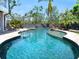 Luxury pool with integrated spa and rock waterfall feature, blending seamlessly with the backyard at 7333 Point Of Rocks Rd, Sarasota, FL 34242
