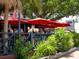 Outdoor dining area at waterfront restaurant with red umbrellas and lush landscaping at 734 Canal Rd, Sarasota, FL 34242
