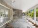 Empty sunroom with ceiling fan, concrete floors, and wall to wall windows showcasing view of the outdoors at 734 Canal Rd, Sarasota, FL 34242