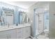 Bright bathroom with double sinks, marble countertops, vanity lighting, and a glass-enclosed shower at 750 Bayport Way # 750, Longboat Key, FL 34228