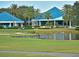 The lush golf course overlooks the beautiful clubhouse with blue roofs, golf cart, and serene pond at 7624 Boltons Ct, Bradenton, FL 34201