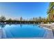 Community pool with clear blue water surrounded by mature trees and plentiful lounge seating at 111 Tidy Island Blvd # 111, Bradenton, FL 34210