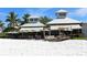 Exterior view of beachfront restaurant with outdoor seating, awnings, and lush palm trees at 111 Tidy Island Blvd # 111, Bradenton, FL 34210