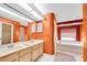 This bathroom features an orange accent wall, double vanity, and tub with jets at 1143 131St E St, Bradenton, FL 34212