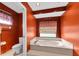 This bathroom features an orange accent wall, toilet, and tub with jets at 1143 131St E St, Bradenton, FL 34212