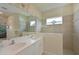 Bathroom featuring a double sink vanity, large mirror, tiled shower, and natural light at 12330 Halfmoon Lake Ter, Bradenton, FL 34211