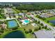 Aerial view displaying the neighborhood, tennis court, pool, playground, lake, and lush landscaping at 12330 Halfmoon Lake Ter, Bradenton, FL 34211