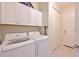 Well-equipped laundry room featuring a washer, dryer, and storage cabinets at 12330 Halfmoon Lake Ter, Bradenton, FL 34211
