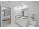 Bathroom boasts double sinks, granite counters, white cabinets, decor, with a peek into the neutral bedroom at 13422 Willow Bluestar Loop, Riverview, FL 33579