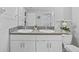 Stylish bathroom with double sinks, granite counters, white cabinets, neutral paint, and decorative plants at 13422 Willow Bluestar Loop, Riverview, FL 33579