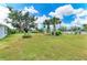 Expansive grassy backyard with mature trees under a beautiful sky with fluffy white clouds at 1364 Westport Ln # 1403, Sarasota, FL 34232
