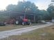 Red tractor parked next to a metal barn and tools at 15308 Fruitville Rd, Sarasota, FL 34240