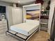Cozy bedroom featuring a Murphy bed with side storage, closet, and mountain scenery wall art at 15308 Fruitville Rd, Sarasota, FL 34240