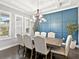 Dining room featuring a modern chandelier, a blue accent wall, and plantation shutters at 16614 Berwick Ter, Lakewood Ranch, FL 34202
