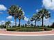 Community entrance featuring a decorative fountain, manicured landscaping, and palm trees against a blue sky at 16614 Berwick Ter, Lakewood Ranch, FL 34202
