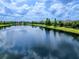 Panoramic view of a serene lake reflecting the clear blue sky, surrounded by well-manicured neighborhood at 16614 Berwick Ter, Lakewood Ranch, FL 34202
