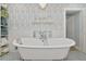 A clawfoot tub with stylish fixtures is complemented by a shelf and patterned wallpaper at 1722 Hazelwood St, Sarasota, FL 34231