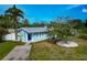 Charming blue home with a well-manicured front yard, palm trees, and a paved driveway at 1722 Hazelwood St, Sarasota, FL 34231