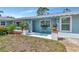Charming light blue home featuring a welcoming front porch with seating, plants, and a well-manicured lawn at 1722 Hazelwood St, Sarasota, FL 34231