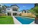 Home back view showcasing a sparkling pool, lush green lawn, and modern architectural design at 2249 Oak Terrace Ter, Sarasota, FL 34231