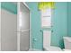 Modern bathroom with a glass shower, window, and bright, refreshing turquoise walls at 2435 Terry Ln, Sarasota, FL 34231