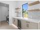 Modern bar with built-in wine cooler, sleek cabinets, open shelving, and decorative tile accents near laundry at 2554 Arlington St, Sarasota, FL 34239