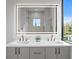 Modern bathroom with double vanity, illuminated mirror, and a view to the backyard through a window at 2554 Arlington St, Sarasota, FL 34239