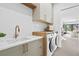 Bright laundry room with white subway tile, wood countertop, front load machines, and gold fixtures at 2554 Arlington St, Sarasota, FL 34239